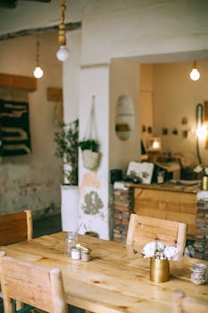 Table with flowers in small vase near chairs under shiny lamps in old house